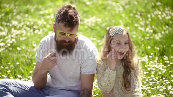 最好的朋友概念爸爸和女儿坐在草地上绿色的背景家庭在户外休闲视频的预览图
