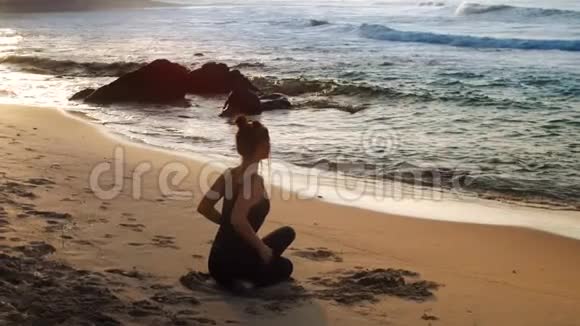 美妙的女孩坐在放松瑜伽姿势的背面观看视频的预览图