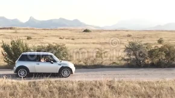 两个年轻女子在一座山脉的背景下坐着一辆车视频的预览图
