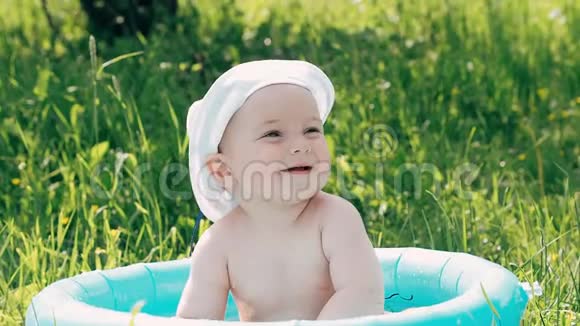 小男孩宝宝在一个充气的游泳池里洗澡在夏天微笑肥皂泡视频的预览图