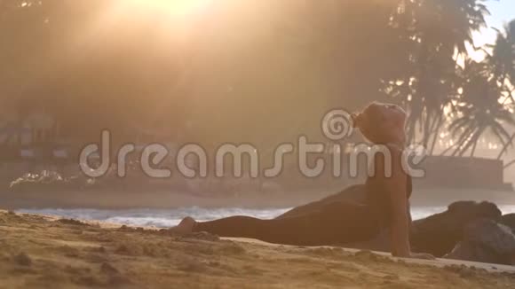 年轻女子伸展肌肉在海边做瑜伽视频的预览图
