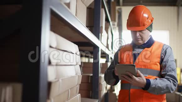穿着头盔和工作服的工人站在货架旁边在ipad上发布关于缺少工具的通知视频的预览图