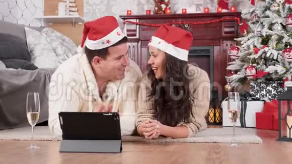 圣诞前夜一对情侣躺在地板上用平板电脑上网购物视频的预览图