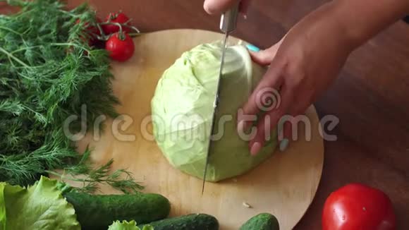一个女人的特写在一个木制的砧板上把一把刀切成半个卷心菜4K视频的预览图