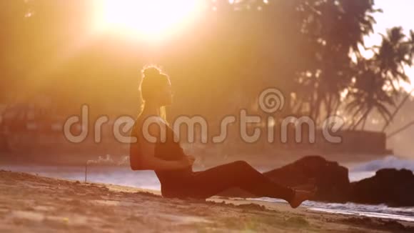 赤脚女孩坐在沙滩上棕榈树的轮廓视频的预览图