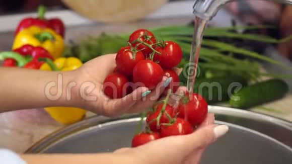 一个年轻女孩在家里的水槽里洗成熟的樱桃番茄4K视频的预览图