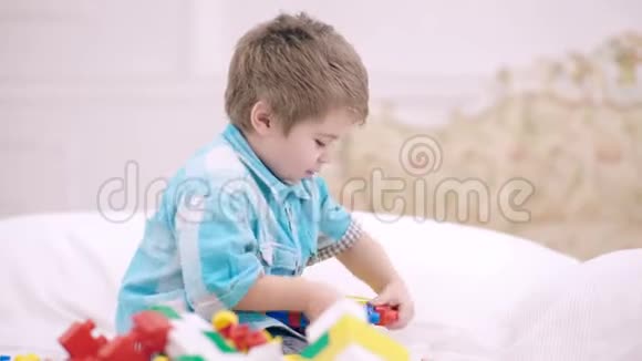 幼儿玩五颜六色的玩具积木孩子们玩小男孩在白色的床上搭建积木玩具塔视频的预览图