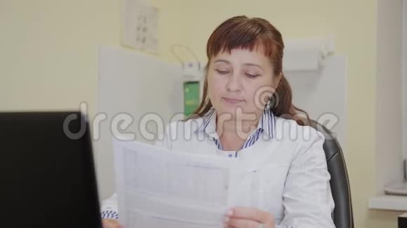 一位老年妇女医生从打印机上取一个测试结果并检查它视频的预览图