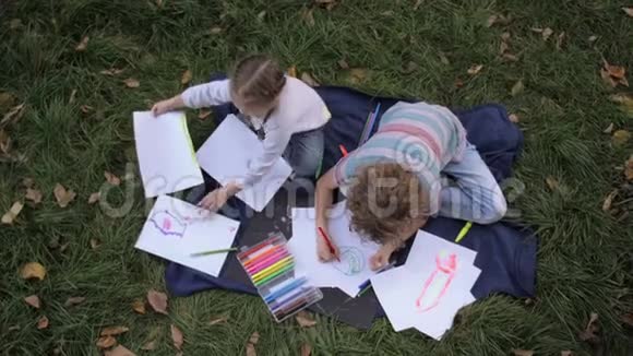 两个快乐的孩子男孩和女孩躺在夏日公园的绿草地上孩子们的兄弟姐妹是读书画画玩耍大笑视频的预览图