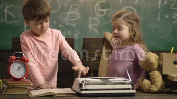回学校去男孩和女孩坐在一张桌子上桌子上有一个绿色的学校黑板背景上的打字机教育朋友视频的预览图
