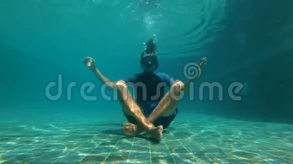 慢动作水下拍摄一个年轻人在瑜伽姿势冥想游泳池底部的概念视频的预览图