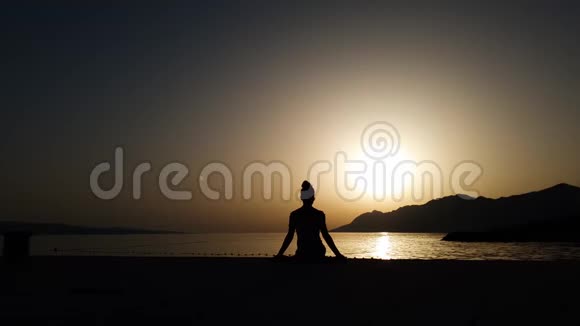 日落时分在海边坐着瑜伽姿势的女性剪影空间自由视频的预览图