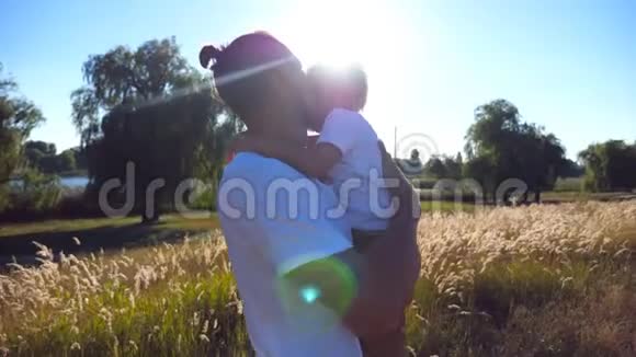 年轻的爸爸牵着他的孩子在草地上抚摸他在一个阳光明媚的日子父亲安慰他的小儿子视频的预览图