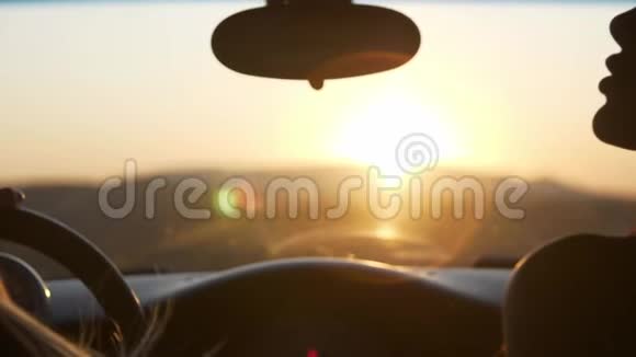 2坐在汽车里的两个年轻女人看日落从车窗里可以看到群山视频的预览图