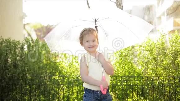 小女孩带着雨伞在公园的小路上微笑慢动作视频的预览图