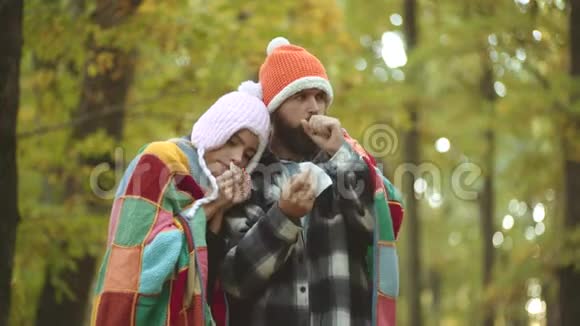 带手帕的年轻夫妇近秋树鼻雨刷秋黄公园打喷嚏视频的预览图