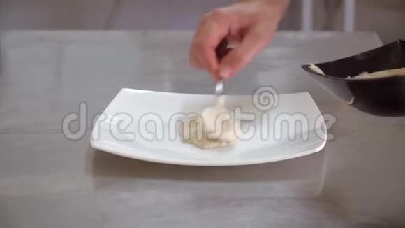 厨师把白酱放在盘子里手的特写动作视频的预览图