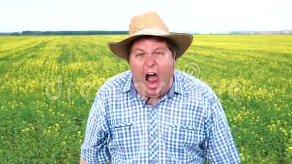 农夫站在田野里在阳光明媚的日子里戴着帽子惊恐地尖叫视频的预览图