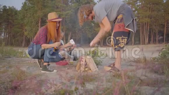 年轻的嬉皮士和他的女朋友在朋友弹吉他的背景下和伍兹闹火视频的预览图