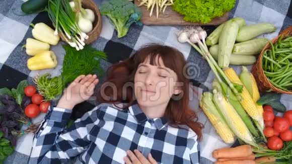 肖像美丽的女农民闭着眼睛躺在一个格子间新鲜的有机蔬菜上景视频的预览图