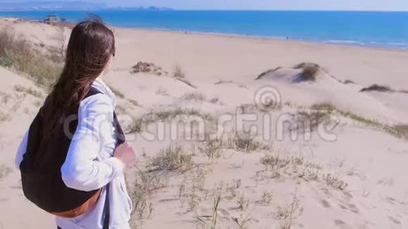 带着背包的女旅行者正在度假的沙滩上四处寻找视频的预览图