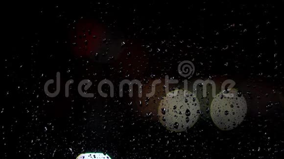 雨滴在夜晚从窗户玻璃上流下来窗外有雨滴的街道灯视频的预览图
