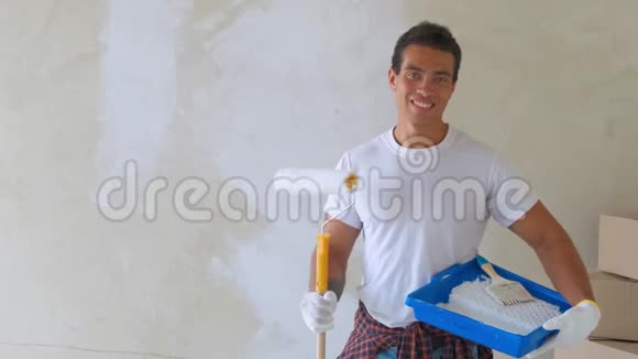 微笑的帅哥在家用滚筒画墙维修建筑和家居概念视频的预览图