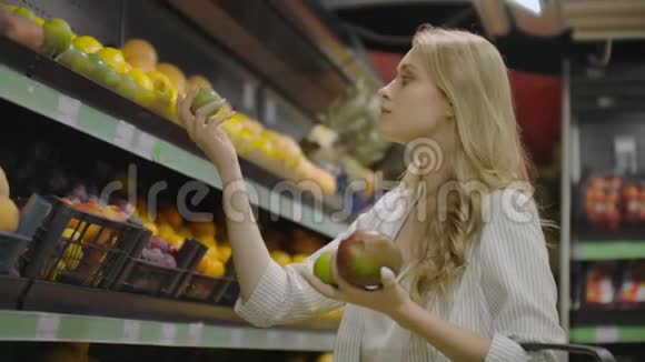 年轻的女人在杂货店里选择熟芒果纯素零废物女孩购买水果和有机织品视频的预览图