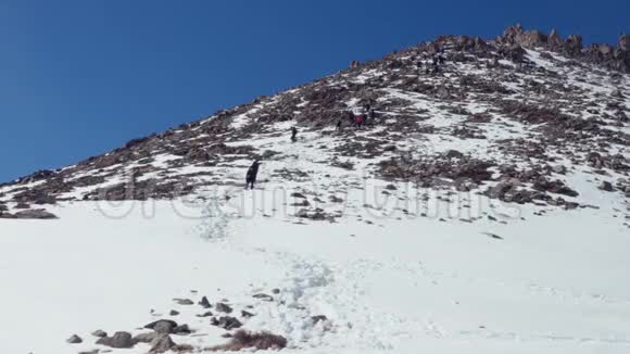 疲惫的登山者沿着白雪覆盖的小路从一座岩石山上下来冬季视频的预览图