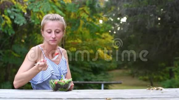 坐在公园里吃新鲜沙拉的女人健康素食食品视频的预览图