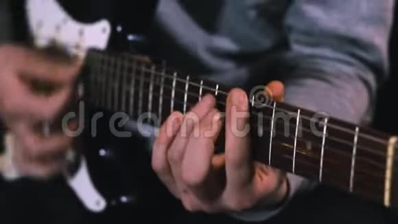吉他手敲击电吉他的琴弦以缓慢的动作合上男人的手指在吉他上弹奏音乐视频的预览图