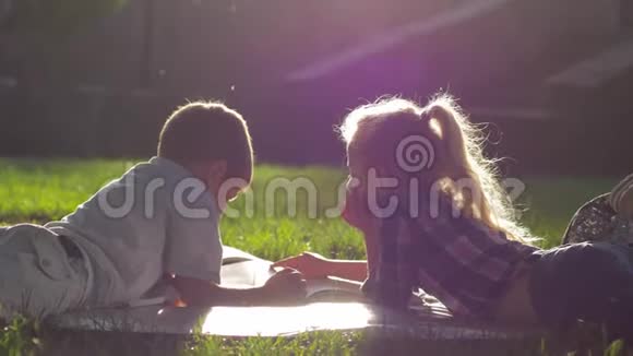闲暇时间的活动好奇的孩子在学校休息的时候在户外的草地上看书视频的预览图
