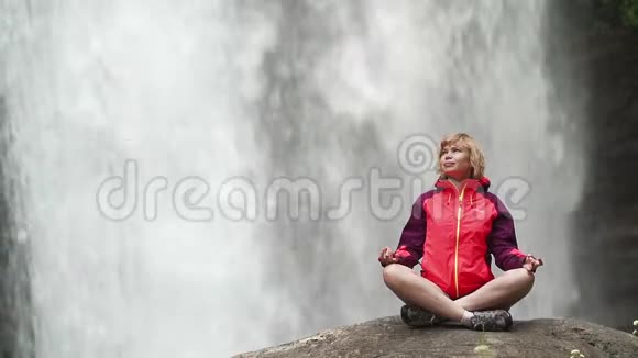 女人做瑜伽姿势莲花对面大瀑布视频的预览图