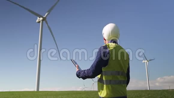 专家站在附近的风力机使用平板电脑制作视频的预览图