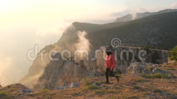 年轻人走在悬崖边从高山上看到美丽的戏剧性的五彩缤纷的日落视频的预览图