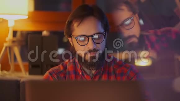 一个人在笔记本电脑上用眼镜工作的肖像关上门商人看监视器视频的预览图