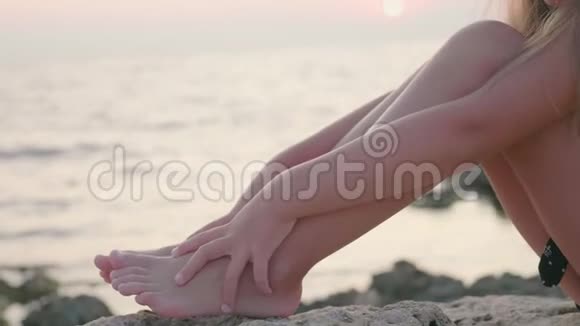 女孩坐在沙滩上抱着膝盖看着大海视频的预览图