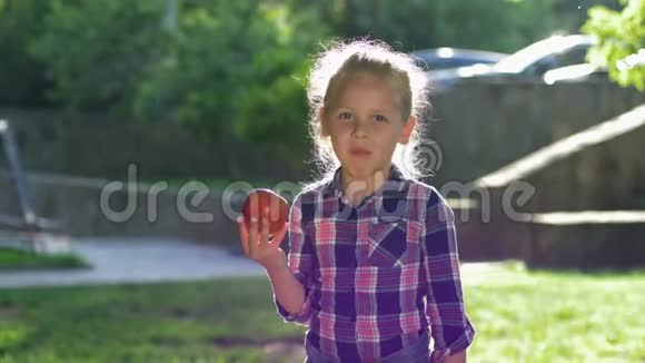 在背光下吃孩子的肖像金发小女孩咀嚼成熟多汁的苹果在露天看镜头视频的预览图