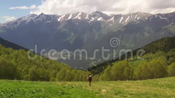 旅游女孩穿着紧身裤背着背包和徒步旅行杆在斜坡山上行走视频的预览图