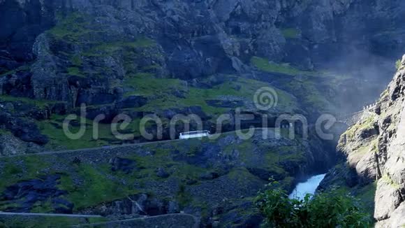 旅游教练巴士上升到Trollstigen或Troll路径并跨越石拱桥瀑布细微的变焦视频的预览图