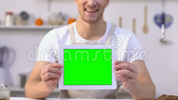 开朗的单身汉手持平板电脑绿色屏幕食品配送服务应用程序视频的预览图
