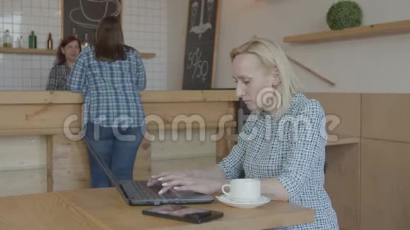 一位严肃的女性博客写手在咖啡馆里工作视频的预览图