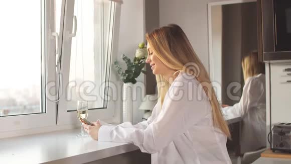 年轻的金发女郎穿着男士衬衫喝香槟视频的预览图