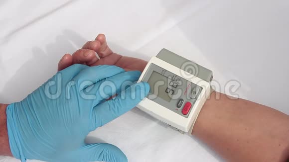 医生带着蓝色手套准备用数字血压计测量病人的血压和心率视频的预览图