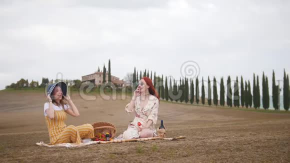 两个女人在野餐吃水果聊天托斯卡纳柏树路视频的预览图