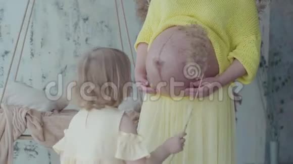 小女孩亲吻她母亲怀孕肚子慢动作视频的预览图