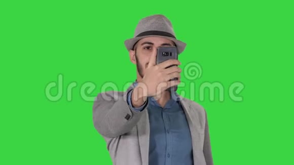 阿拉伯男人穿着休闲服装在绿色屏幕上散步和自拍Chroma键视频的预览图
