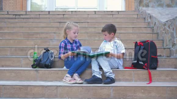 学校里小同学带着背包坐在台阶上在户外休息时看书上的照片视频的预览图