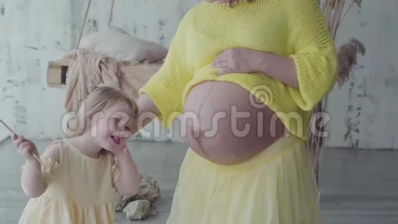 小女孩和她母亲怀孕的肚子慢动作视频的预览图