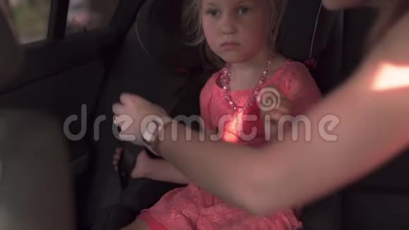 安全带系上儿童汽车座椅母亲和女儿年轻的白种人妈妈穿着夏天的鲜艳的生动视频的预览图